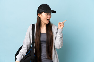 Young sport Chinese  woman with sport bag over isolated blue background intending to realizes the solution while lifting a finger up