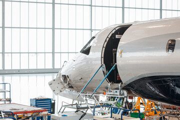 Maintenance of airplane in the large white hangar - obrazy, fototapety, plakaty