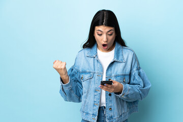 Young brunette girl over isolated blue background surprised and sending a message