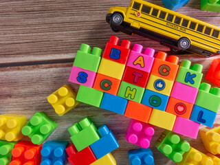 Color toy bricks and school bus on wood table for background or education concept