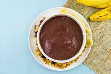 Brazilian açai in a white bowl with banana, granola and chestnuts.