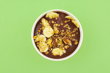 Brazilian açai in a white bowl with banana, granola and chestnuts.