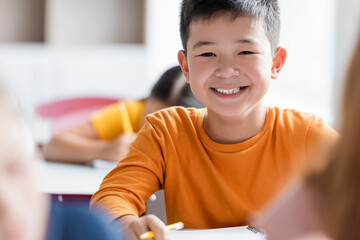 happy asian schoolboy looking at camera during lesson
