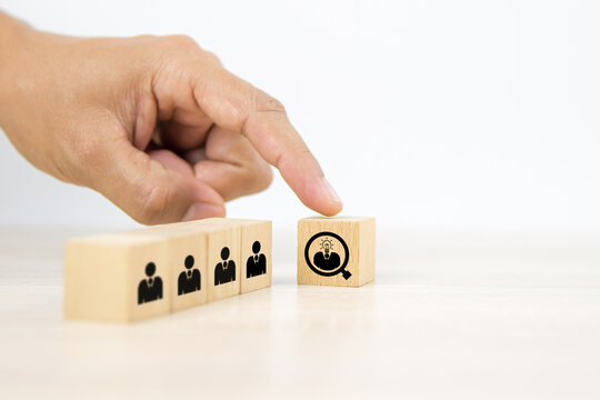 Hand choose human with light bulb icon on cube wooden block stack. Concepts of people business team creative thinking and resources for personnel leader and teamwork or leadership team player.