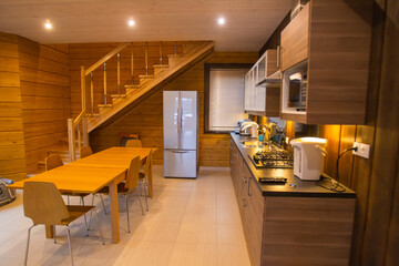 Modern kitchen interior. Kitchen with dining table. Country house with a large kitchen. Dining room interior in a country house. Room for meals in a country hotel. House interior in wood tones