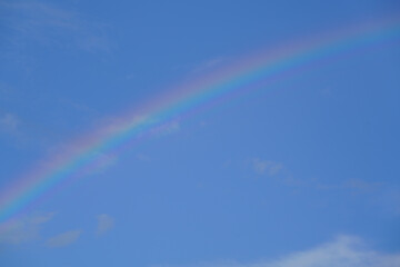 青い空と白い雲にかかる虹