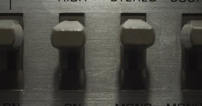 Misc Switches, Separate. Macro extreme close up on a vintage silver brushed metal stereo system as miscellaneous switches get flipped on and off.