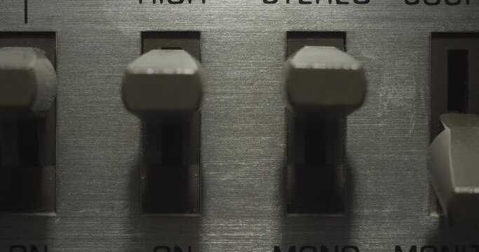Misc Switches, Random. Macro extreme close up on a vintage silver brushed metal stereo system as miscellaneous switches get flipped on and off.