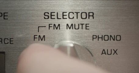 Selector Knob, Random. Macro extreme close up on a vintage silver brushed metal stereo system as an auxiliary selector knob is dialed.