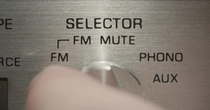 Selector Knob, Random. Macro extreme close up on a vintage silver brushed metal stereo system as an auxiliary selector knob is dialed.