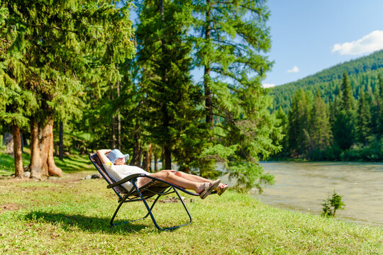 one person relaxing in the camping chair on the beach of river in summertime