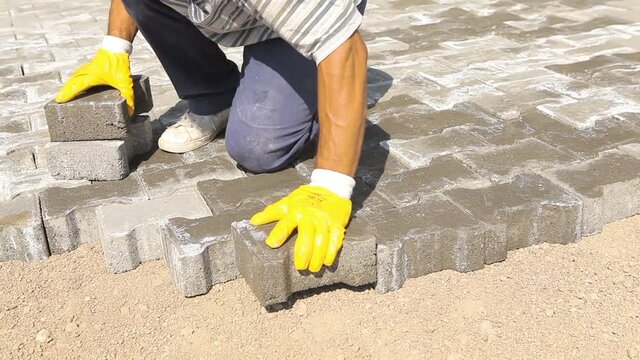Worker laying cobblestone. Gray color keystone road floor background. Working worker. Worker laying keystone with his hands.