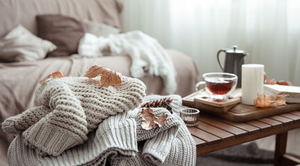 Fototapeta na wymiar Autumn home composition with tea, candle, book and knitted elements.