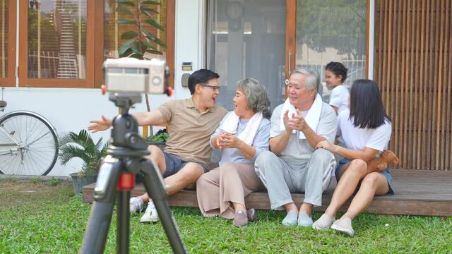 4K Happy multi-generation Asian family relax and having fun together at home. Parents and grandparents with cute baby child girl photography on digital camera together in front of home with happiness