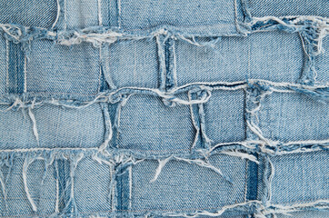Surface of pieces of old tattered denim close