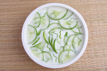Bowl of delicious organic fresh cucumber salad with onion and curd. Healthy vegan diet meal.