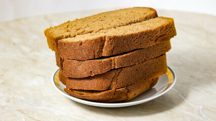 Sliced pieces of black bread are stacked in a plate.