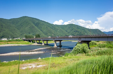 summer scenery of blue sky with clouds, mountain range, and brige over the chikuma river in nagano prefecture, japan
