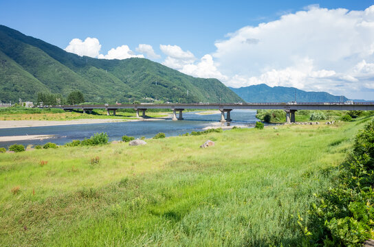 summer scenery of blue sky with clouds, mountain range, and brige over the chikuma river in nagano prefecture, japan