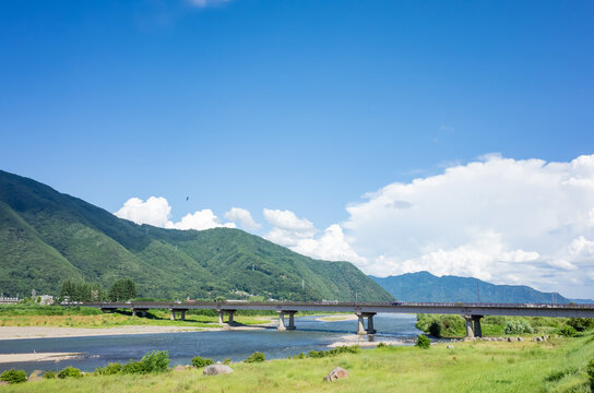 summer scenery of blue sky with clouds, mountain range, and brige over the chikuma river in nagano prefecture, japan