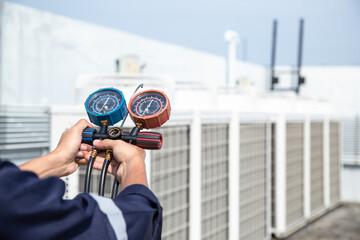 Technician is checking air conditioner ,measuring equipment for filling air conditioners , service and maintenance air conditioner .