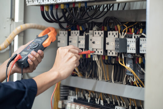 Electrician engineer work tester measuring voltage and current of power electric line in electical cabinet control , concept check the operation of the electrical system .