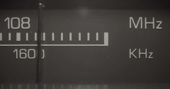 Radio Frequencies 108 MHz / 1600 KHz. Macro extreme close up on a vintage silver brushed metal stereo system as the tuner dials to search for radio stations in the 108 MHz / 1600 KHz range.