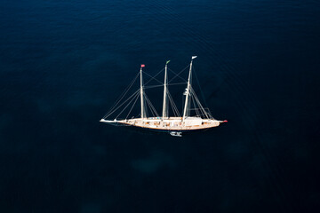 Obraz premium View from above, stunning aerial view of a luxury sailboat sailing on a blue water during a sunny day.Sardinia, Italy