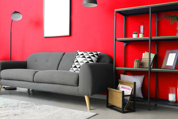 Interior of stylish living room with sofa and shelf unit near red wall