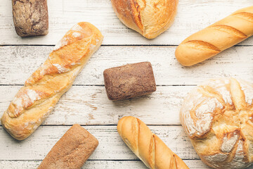 Assortment of fresh bread on white wooden background