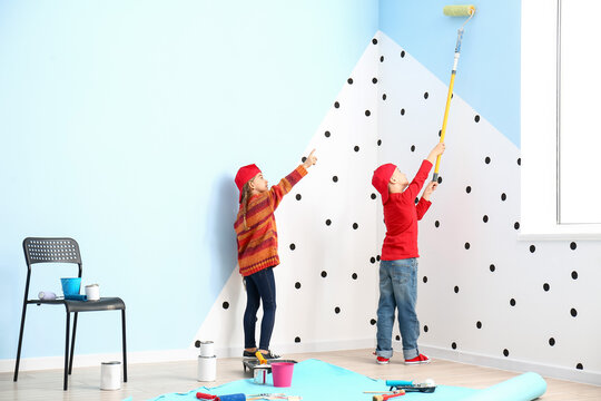 Little children painting wall at home