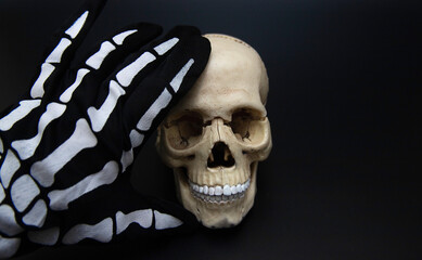Human skull on black background, skeleton hand on skull, Halloween, day of the dead, october 31, scary, horrible gothic background. Anatomical skull.
