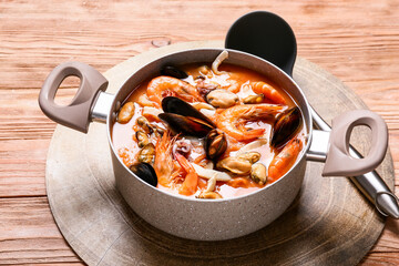 Pot of tasty Cacciucco soup on wooden background