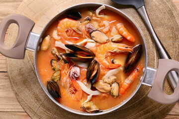 Pot of tasty Cacciucco soup on wooden background