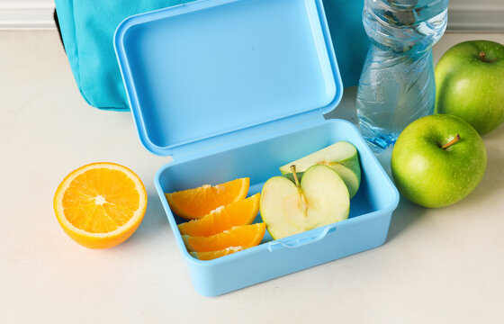 Lunch box with fruits on light background, closeup