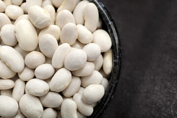 Bowl of raw beans on fabric background, closeup