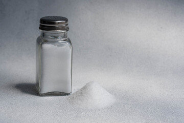 A pile of salt from salt shaker, concept excessive salt intake and white death