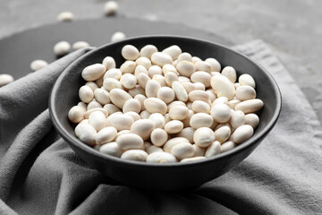 Bowl of raw beans on grey background