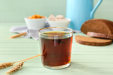 Glass of fresh kvass on color wooden background