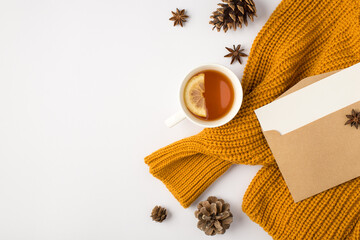 Top view photo of orange pullover cup of tea with lemon anise pine cones and open craft paper...