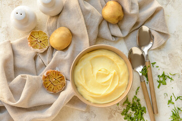 Bowl of tasty mashed potatoes with garlic and vegetables on light background