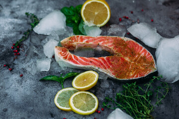 Raw salmon steak with herbs and lemon on gray background