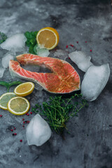 Raw salmon steak with herbs and lemon on gray background
