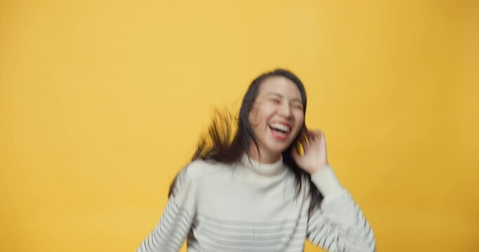 Attractive beauty Asia lady listen music happy and cheerful dancing and waving hands shaking head having fun with enjoy moment., Indoor portrait of relaxed girl isolated on yellow background.