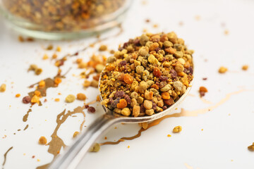Spoon with bee pollen on white background, closeup