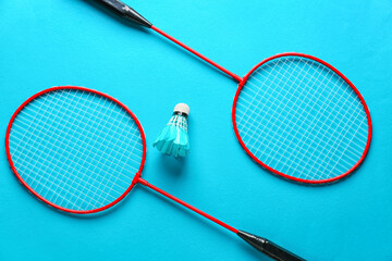 Badminton rackets and shuttlecock on color background