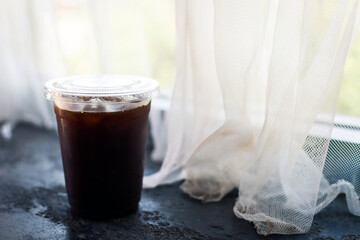 Americano coffee in plastic cup near the window.
