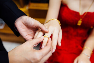 The groom puts an engagement gold ring on the bride's finger, close-up