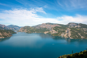 Fototapeta premium Paysage du lac de Serre-Ponçon entouré de montagne autour du village de Le Sauze-du-Lac dans le département des Hautes-Alpes en France en été