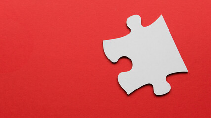 A piece of white jigsaw puzzle on a red background with copy space.